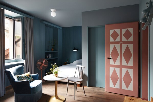 Une chambre moderne avec un lit, une chaise, une table et une grande fenêtre.