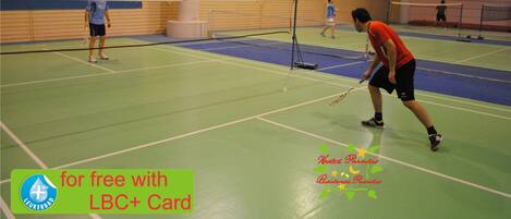 An indoor badminton court with players and a net.