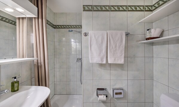 A bathroom with a shower, a sink, a towel rack, and a toilet paper holder. - Hotel-Restaurant Bürchnerhof (Buerchen)