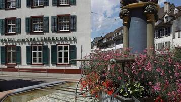 Hotel zum Spalenbrunnen features a charming facade with green shutters and a decorative fountain.