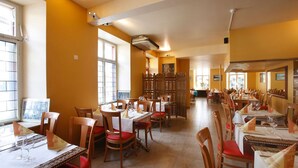 A restaurant with multiple tables and chairs, a wooden partition, and a view of the street through large windows. - Zum Spalenbrunnen (Basel)