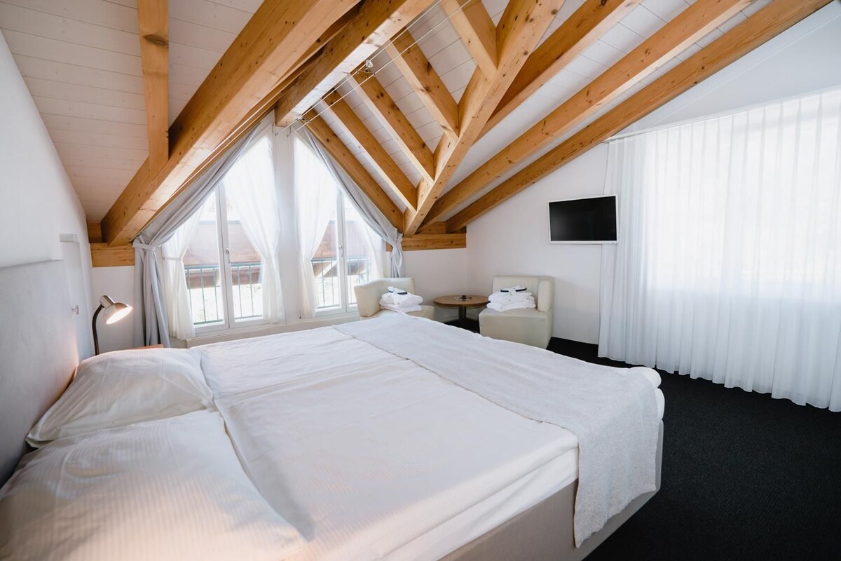 Quarto de hotel com uma cama grande, uma mesa, uma cadeira e uma televisão.