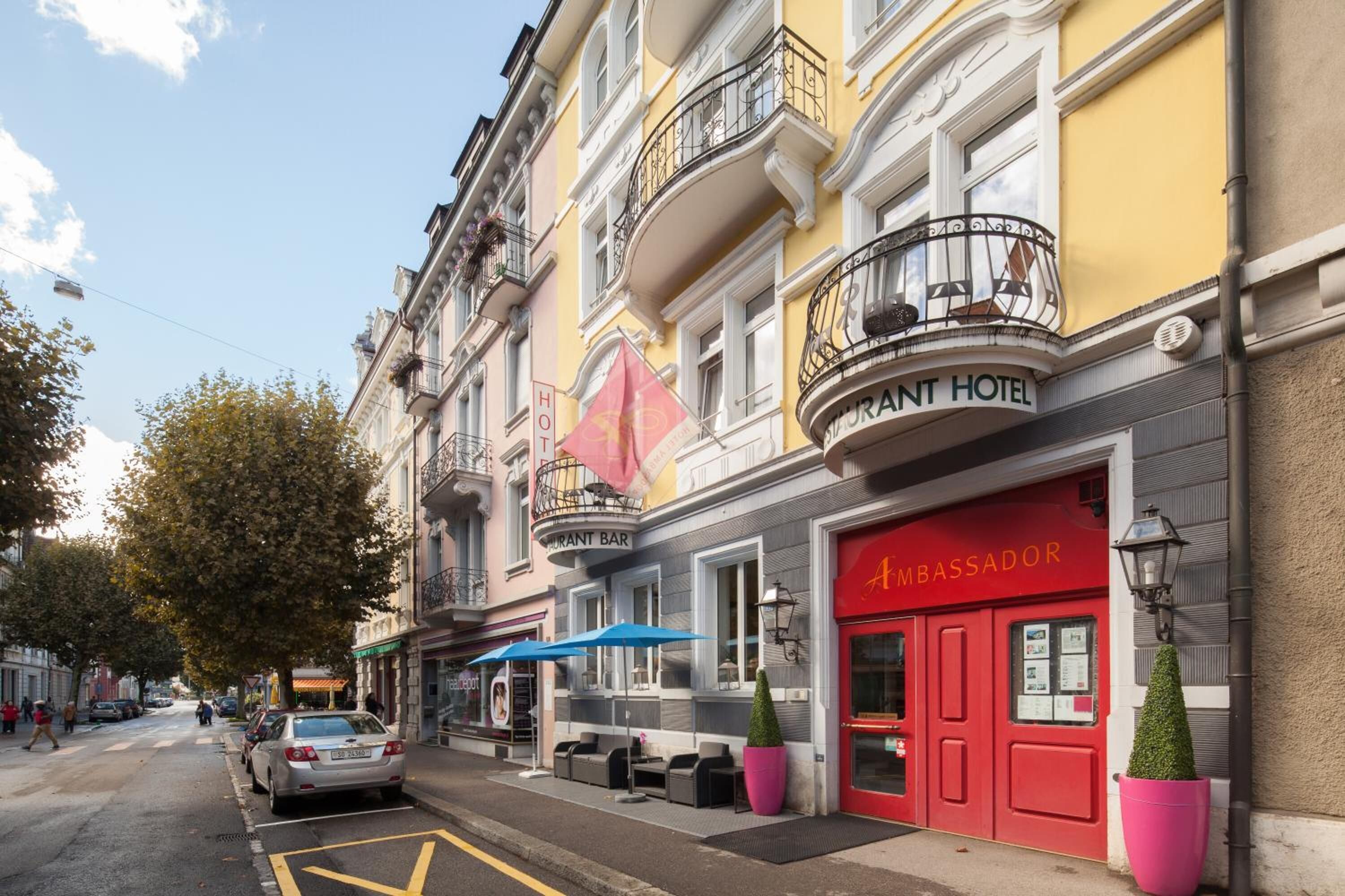 A hotel with a red entrance, a bar, and outdoor seating.