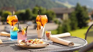 A table with a meal and drinks, set against a mountain backdrop.