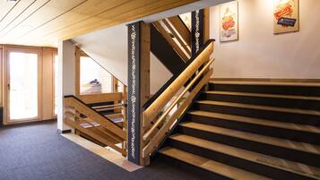 Un escalier en bois avec une rampe, un plancher recouvert de moquette et une porte donnant sur une autre pièce.