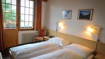 Ett hotellrum med två sängar, en stol, ett skrivbord med en telefon, ett element och två vägglampor.