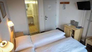 Ein Hotelzimmer mit zwei Betten, einem Schreibtisch, einem Computer, einem Fernseher und einer Lampe.