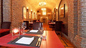 A restaurant with brick walls, wooden tables, and a chandelier.