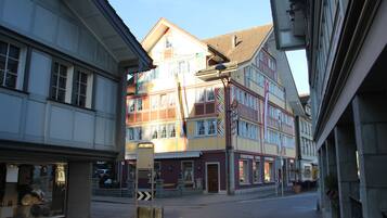 A street view with a building featuring multiple stories, large windows, and a visible storefront.
