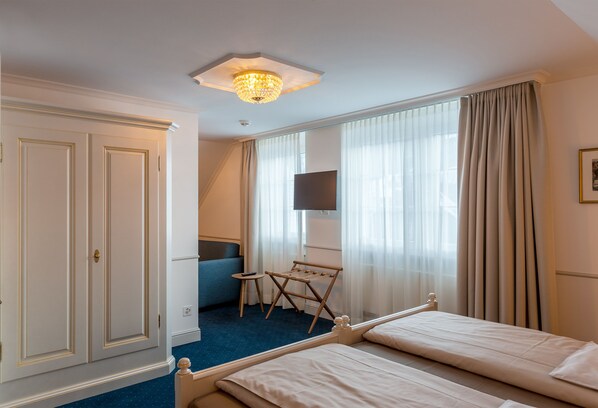 Una habitación de hotel con una cama, un escritorio, una silla, un televisor y un armario.