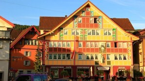 Un edificio a più piani con uno stile architettonico europeo tradizionale, caratterizzato da un tetto a due falde sporgente e un ingresso centrale.
