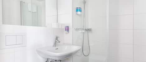 A modern bathroom with a white sink, a glass shower enclosure, and a handheld showerhead.