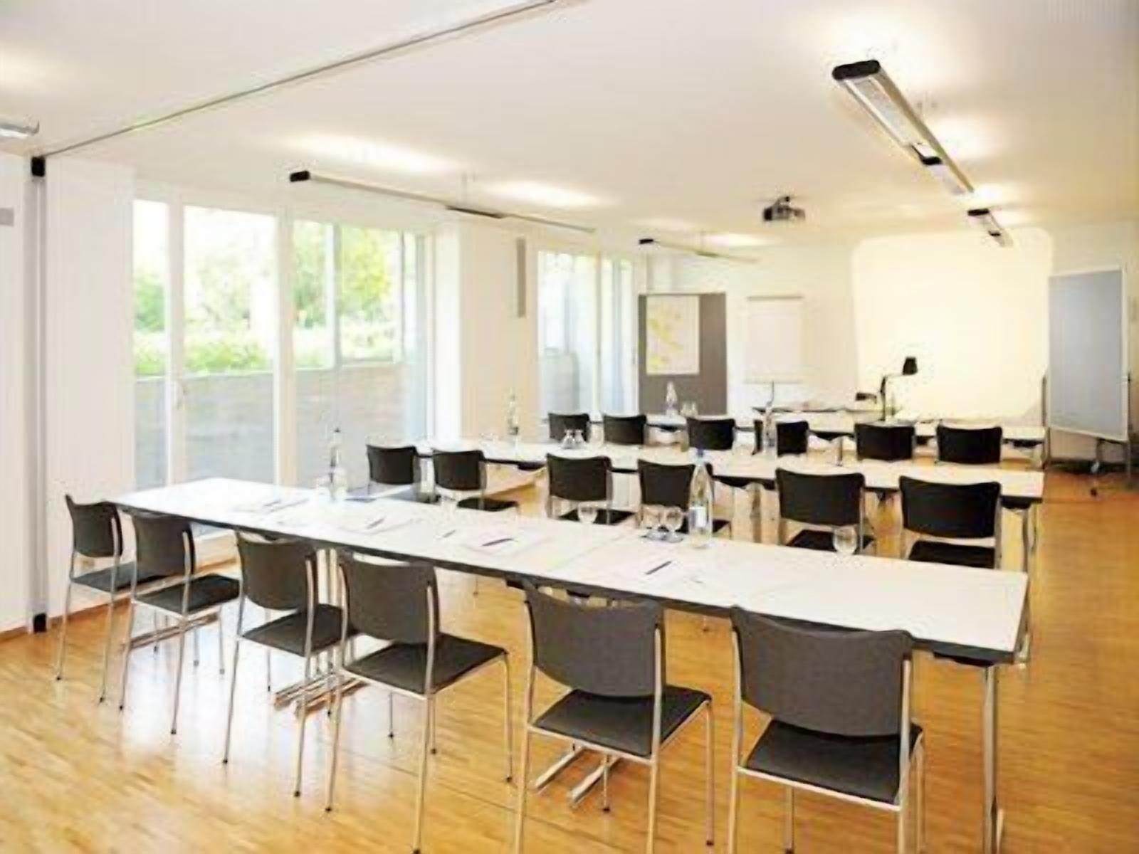 Een vergaderruimte met een lange tafel, meerdere stoelen en een whiteboard.