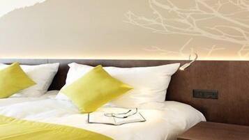 Een hotelkamer met een bed, een nachtkastje en een wand met een ontwerp van een tak.