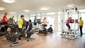 A gym with treadmills, stationary bikes, and a weight machine. - Hotel Artos Interlaken (Interlaken)