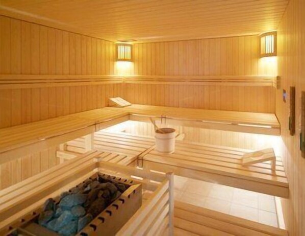 A wooden sauna with benches and a central heating element. - Hotel Artos Interlaken (Interlaken)