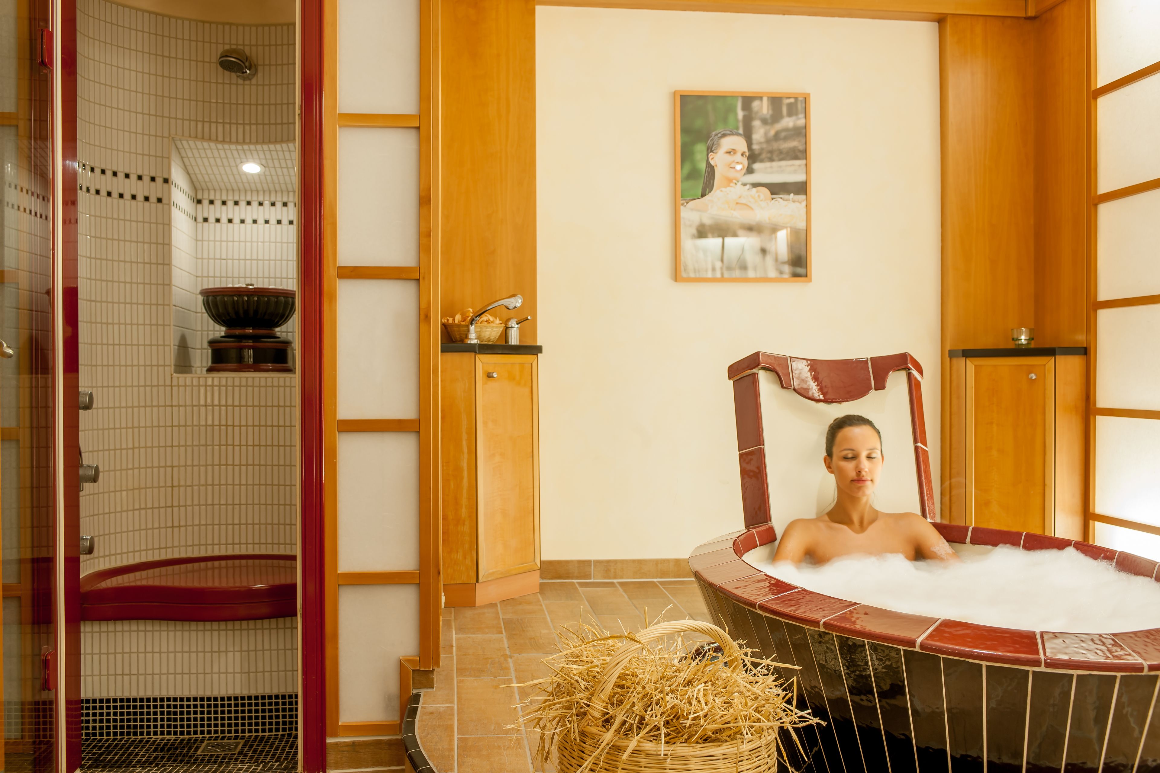 Ett spa-rum med ett bubbelbad, en duschhörna och en väggpanel av trä med en tavla.
