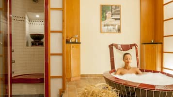Ett spa-rum med ett bubbelbad, en duschhörna och en väggpanel av trä med en tavla.