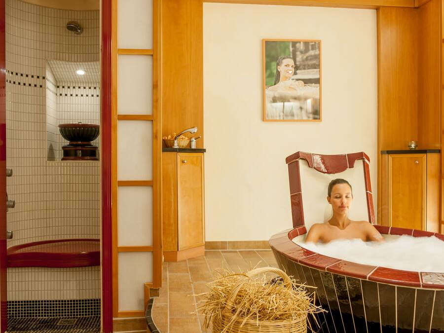 Ett spa-rum med ett bubbelbad, en duschhörna och en väggpanel av trä med en tavla.