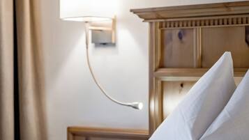 Een hotelkamer met een net opgemaakt bed, een wandlamp en een houten hoofdeinde.