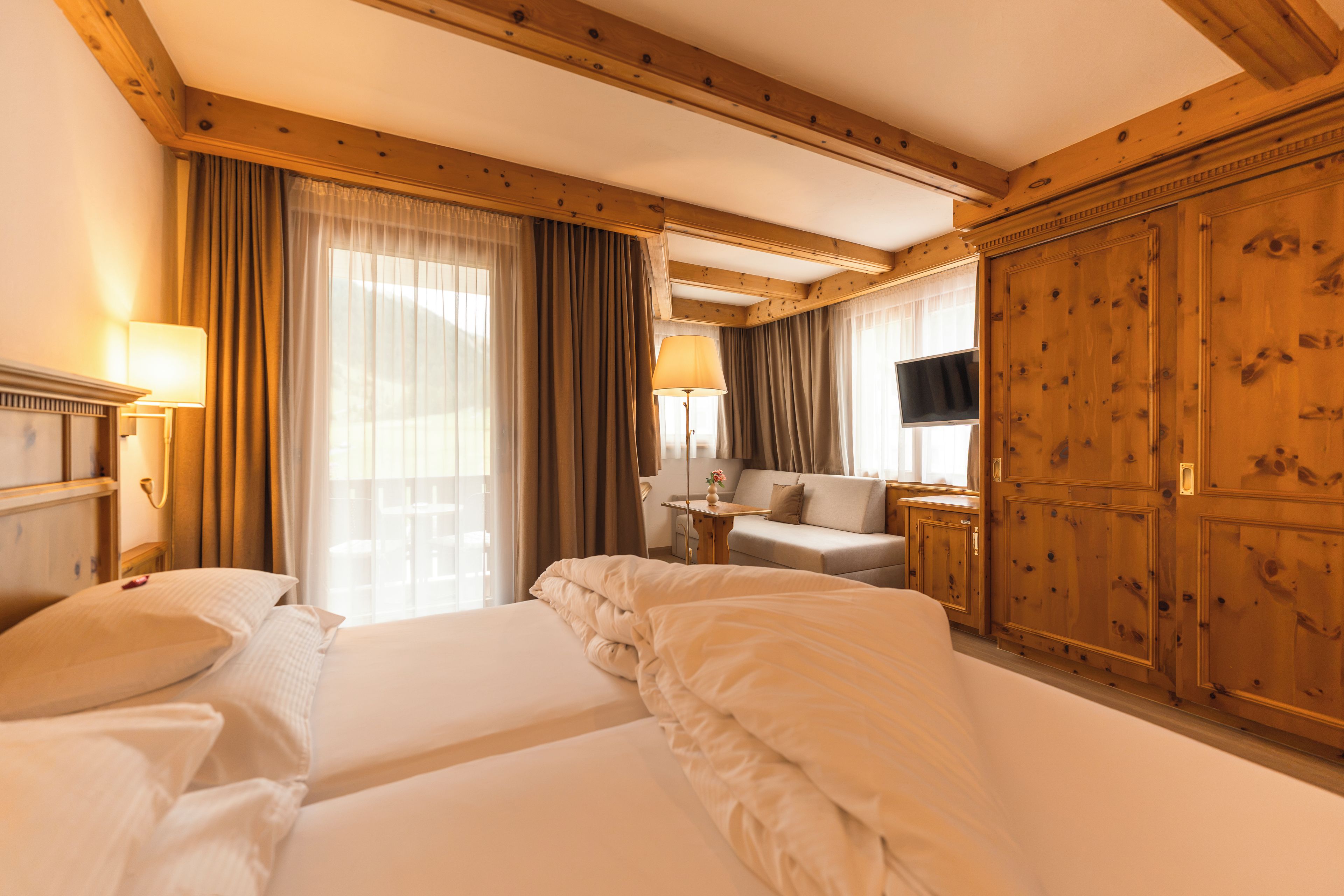 Habitación de hotel con dos camas, televisión, escritorio y un amplio armario de madera.