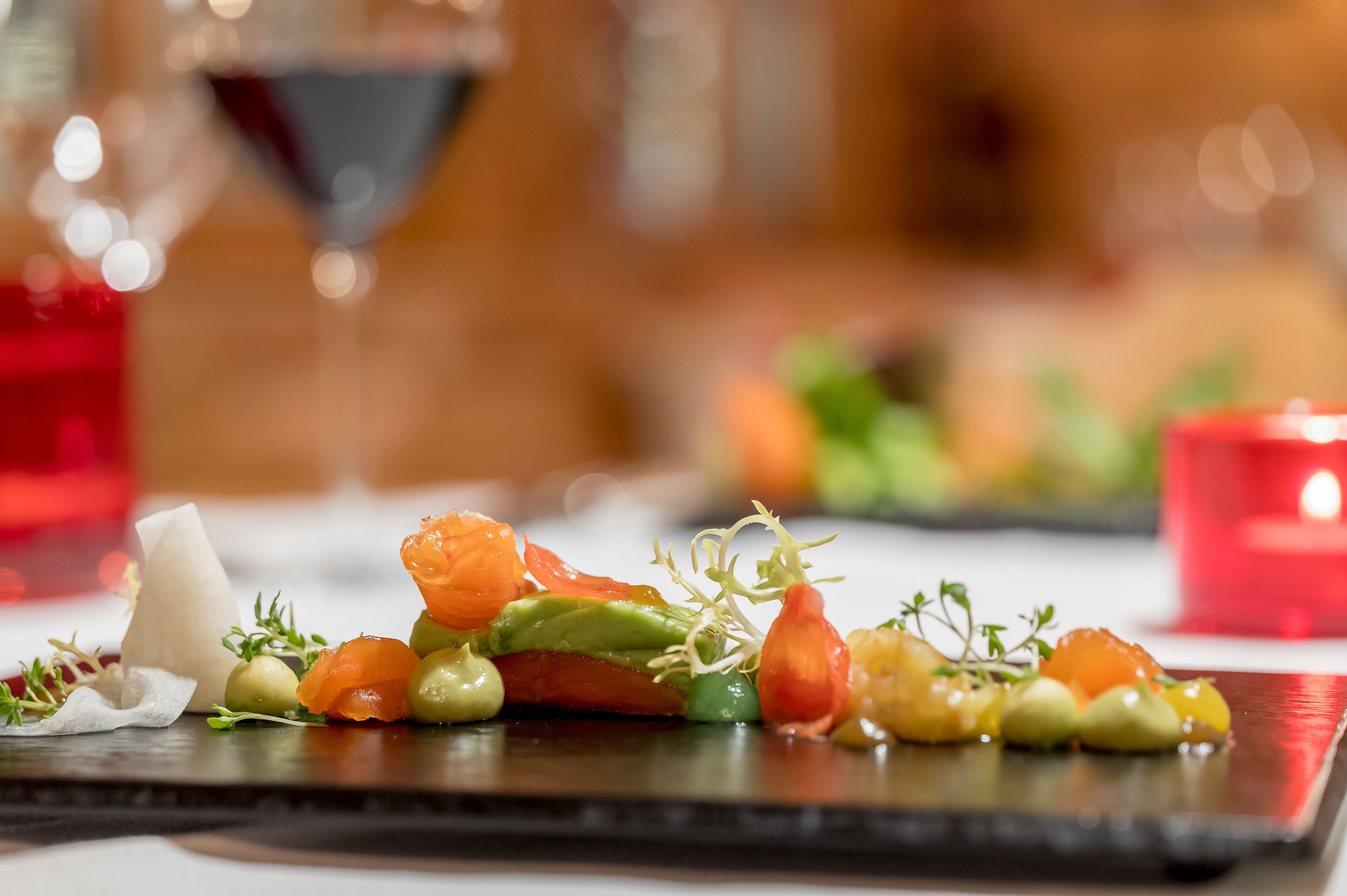 Primer plano de un plato gourmet con varios ingredientes, como salmón, aguacate y vegetales de hoja.