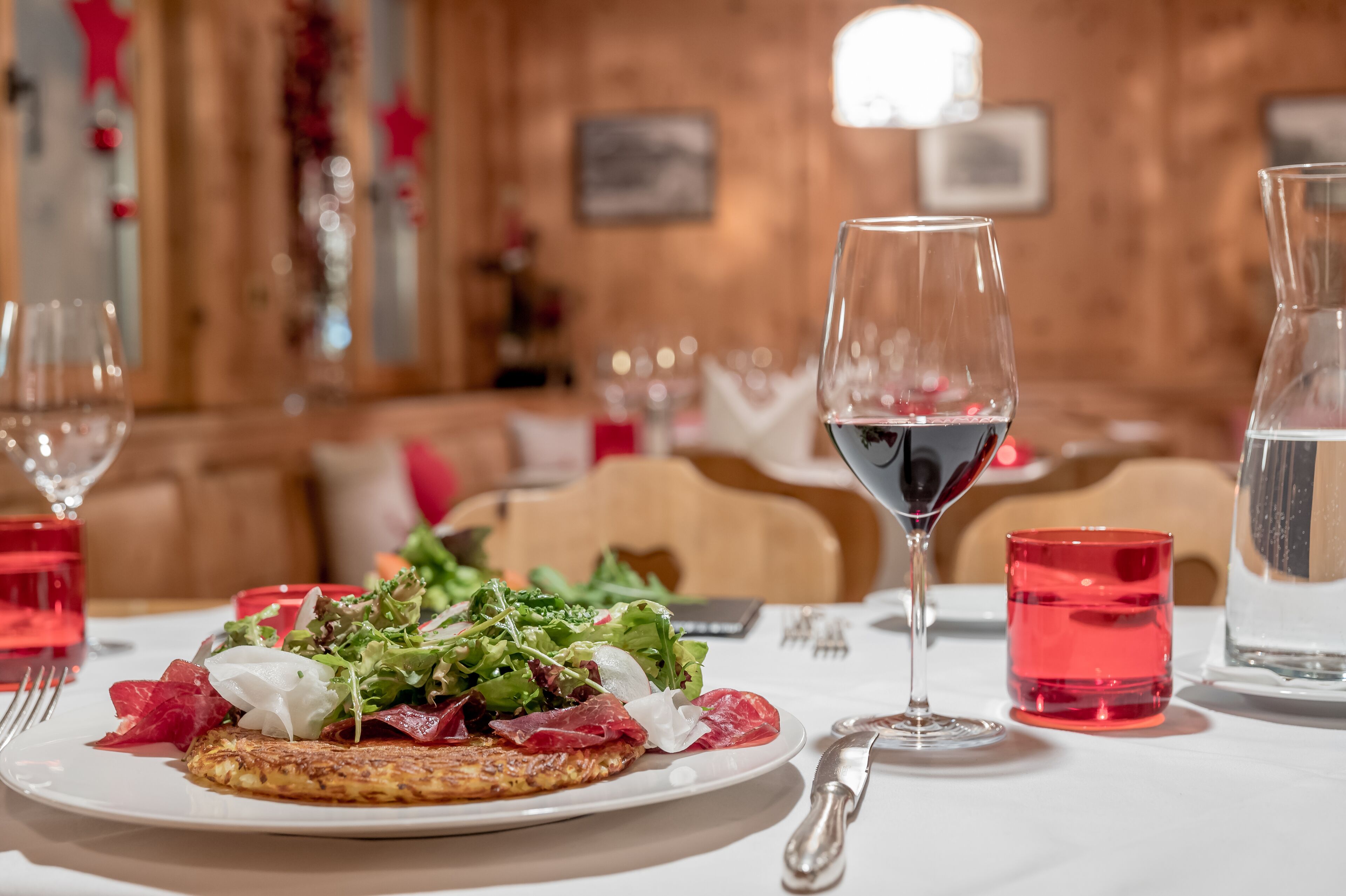 Une table à manger avec une assiette de nourriture, un verre de vin rouge et un verre d’eau.
