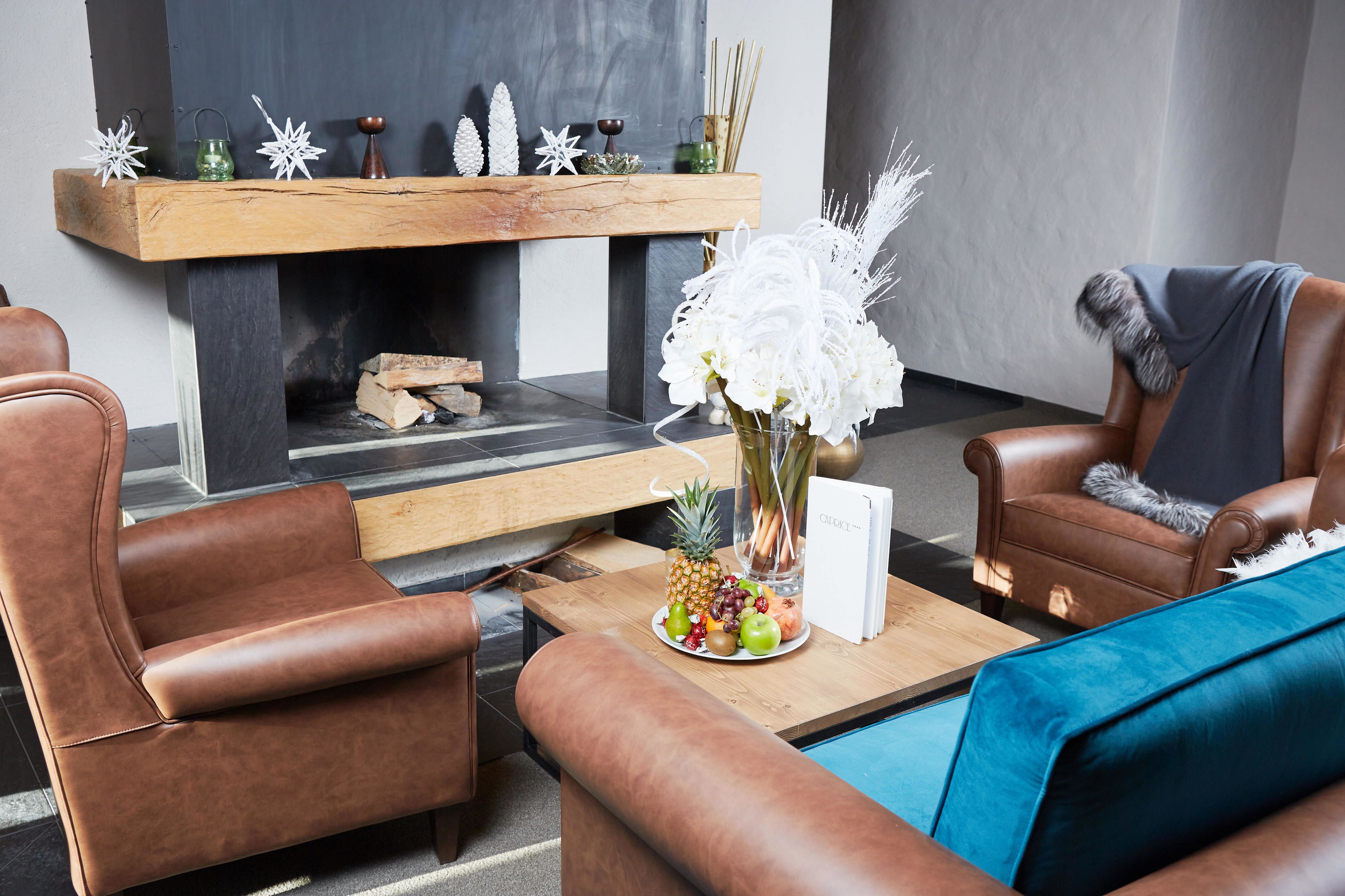 A modern living room with leather sofas, a wooden coffee table with fruit, and a fireplace with decorative items.