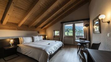 A bedroom with a large bed, a nightstand, a table, and a view of the outdoors.