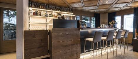 A bar area with wooden paneling, a counter, and bar stools.