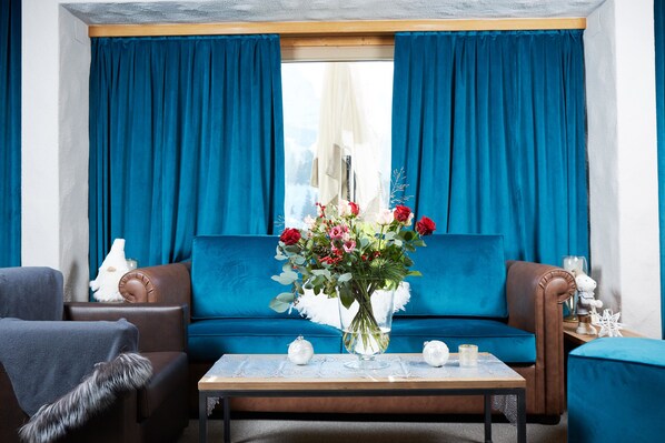 A living room with a sofa, a coffee table, and a vase of flowers.