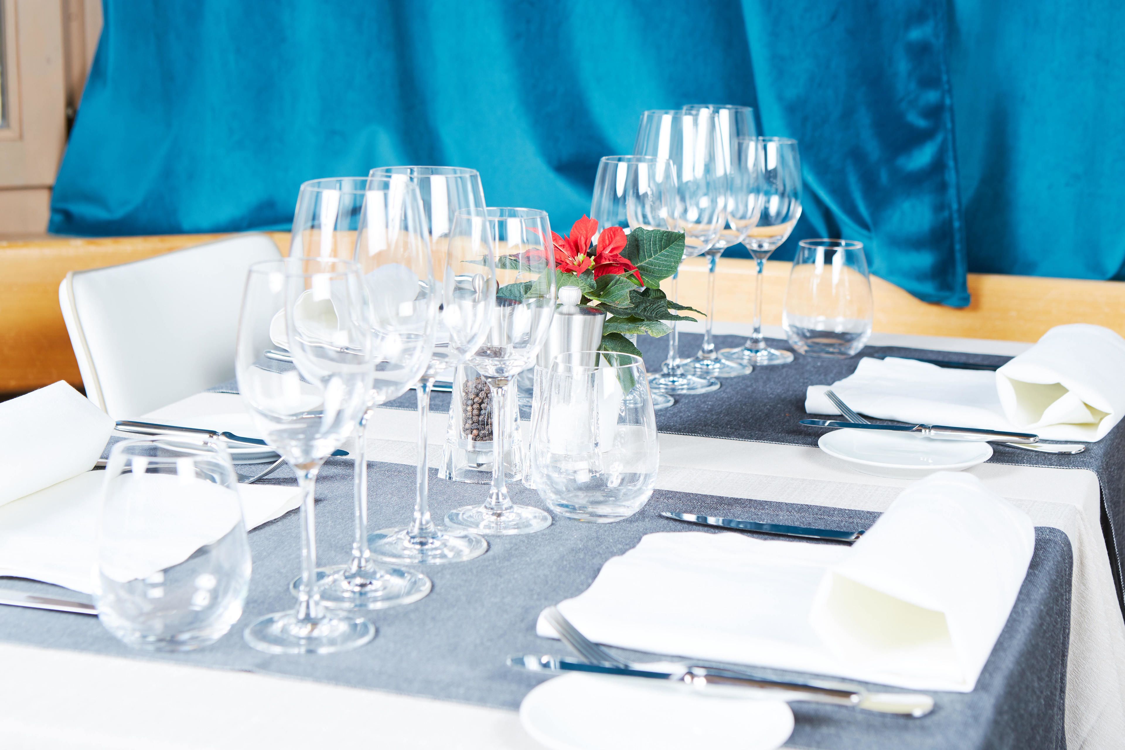 A table set for dining with multiple wine glasses, a vase with a flower, and neatly arranged cutlery.