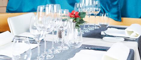 A table set for dining with multiple wine glasses, a vase with a flower, and neatly arranged cutlery.