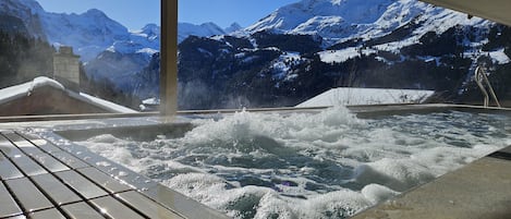 A hot tub with a view of snow-covered mountains.
