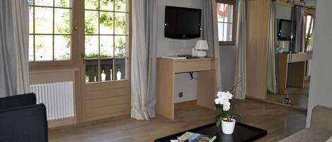 Una sala de estar con un sofá, una mesa de centro con revistas, un televisor y una planta en maceta.