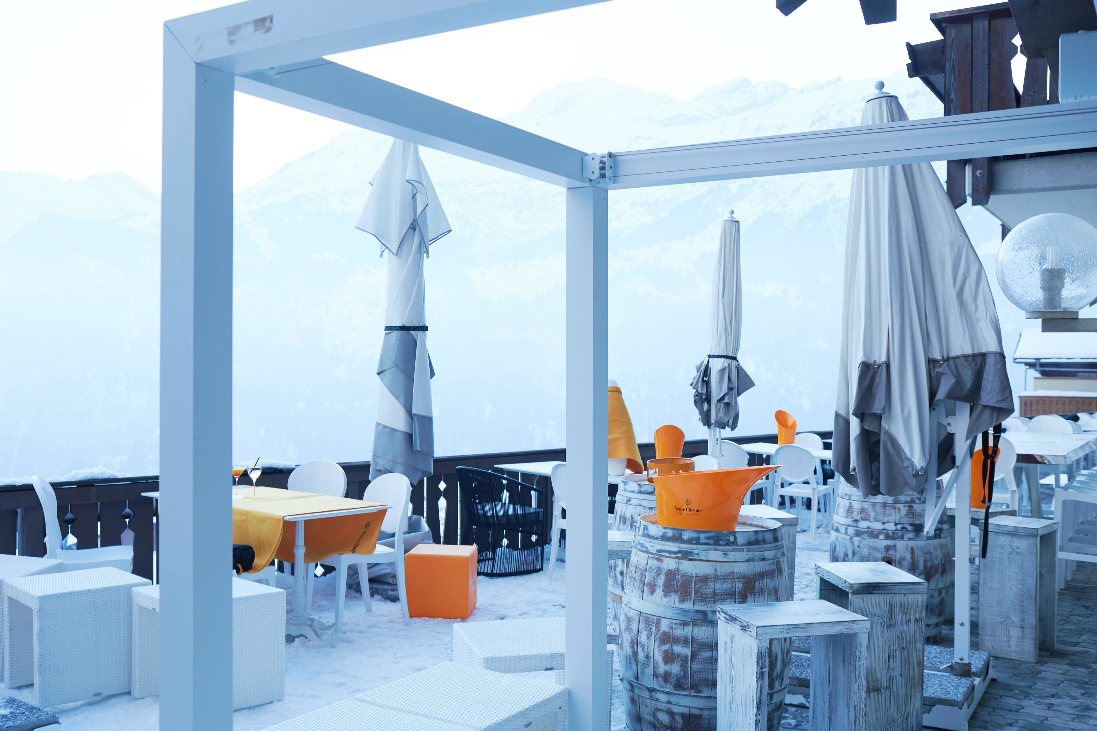 Un espace extérieur aménagé avec des tables, des chaises, des parasols et des barils.