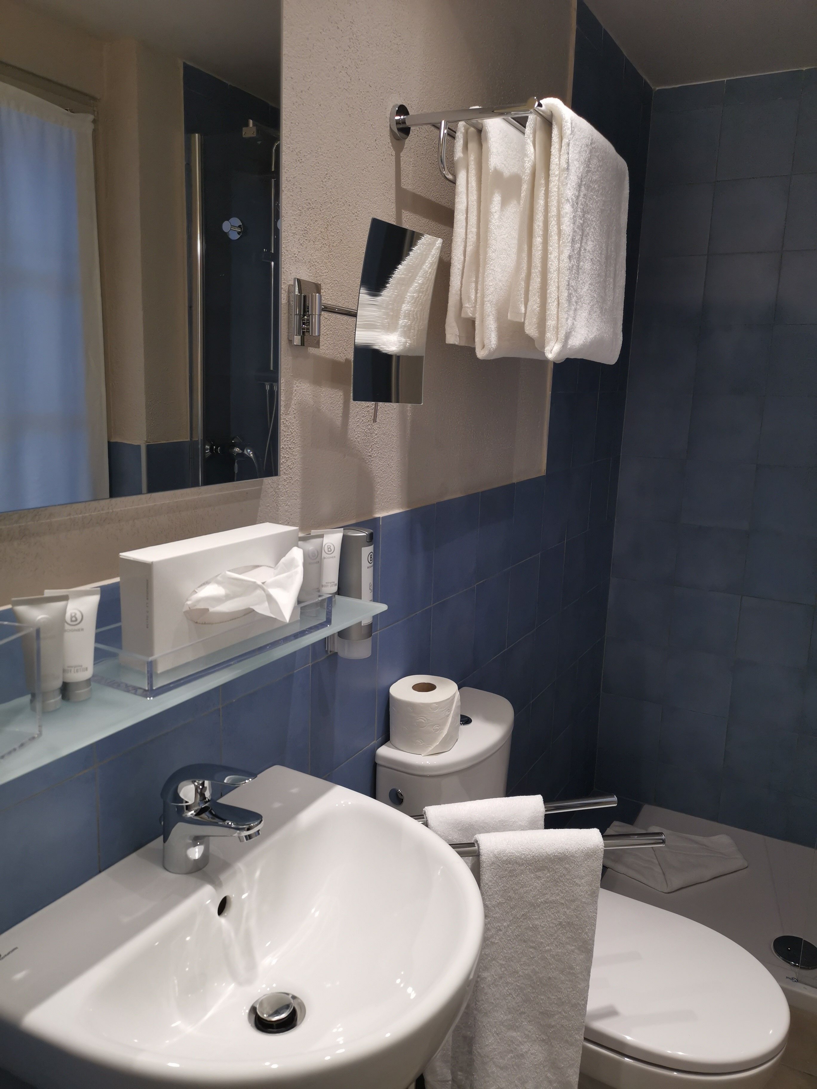 A modern bathroom with a white sink, a mirror, a towel rack, and a toilet.