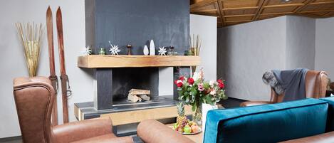 A cozy living room with leather armchairs, a fireplace, and a wooden ceiling.