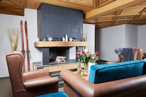 A cozy living room with leather armchairs, a fireplace, and a wooden ceiling.