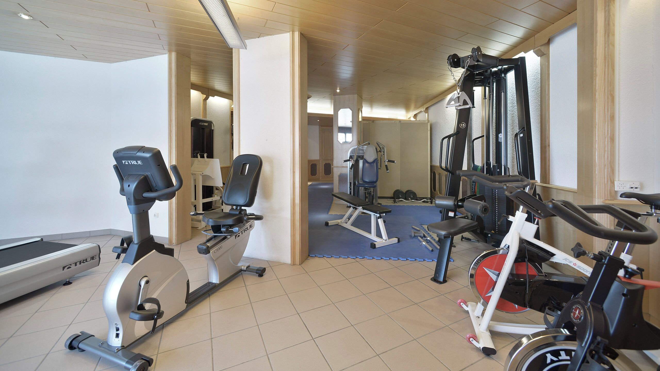 Ein Fitnessstudio mit Trainingsgeräten, Laufband und Spiegelwand.