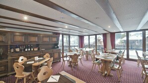 Um restaurante com móveis de madeira, área de bar e grandes janelas com vista para o exterior.
