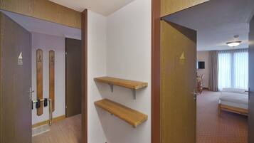 A hotel room with a wooden door, a coat rack, and a bed.