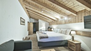Quarto com uma cama grande, uma mesa de cabeceira, uma cadeira e teto de madeira.