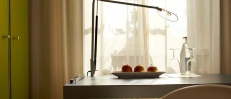 A desk with a lamp, a plate of apples, and a glass of water.