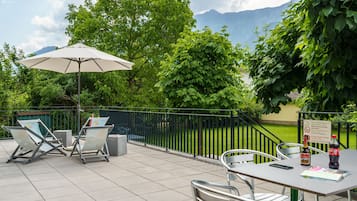 Eine Außenpatio mit Tisch, Stühlen, einem Sonnenschirm und Blick auf Berge.
