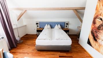 A bedroom with a bed, wooden beams, a nightstand, and a wall-mounted artwork.