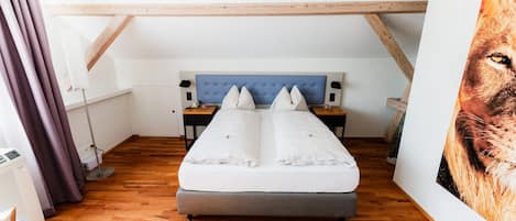 A bedroom with a bed, wooden beams, a nightstand, and a wall-mounted artwork.