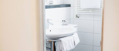 A modern bathroom with a white sink, chrome faucet, and towel rack.
