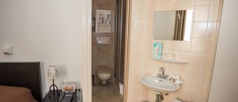 Un baño de hotel con lavamanos, espejo y retrete.