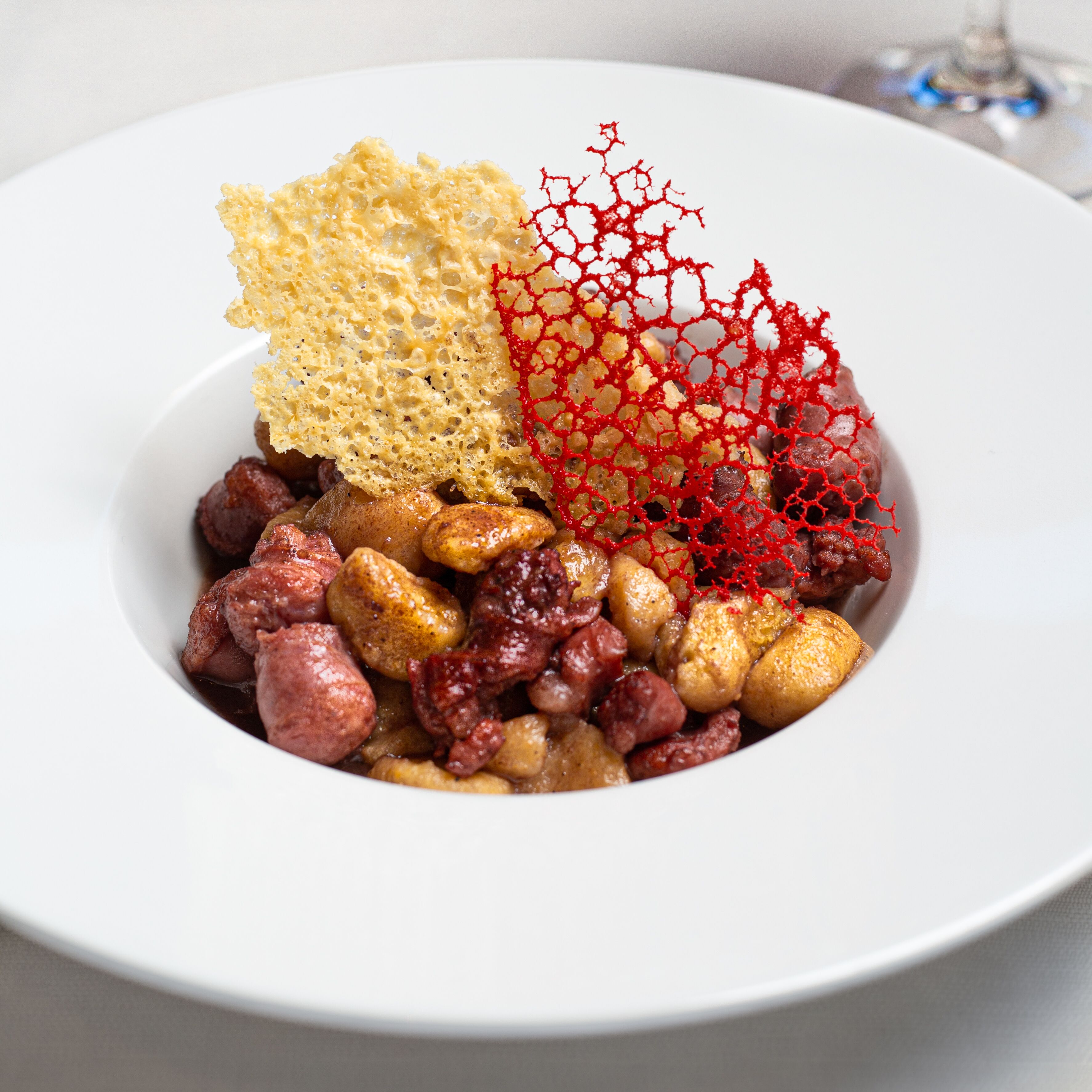 A white plate with a variety of food items including nuts, a piece of bread, and a decorative red element.